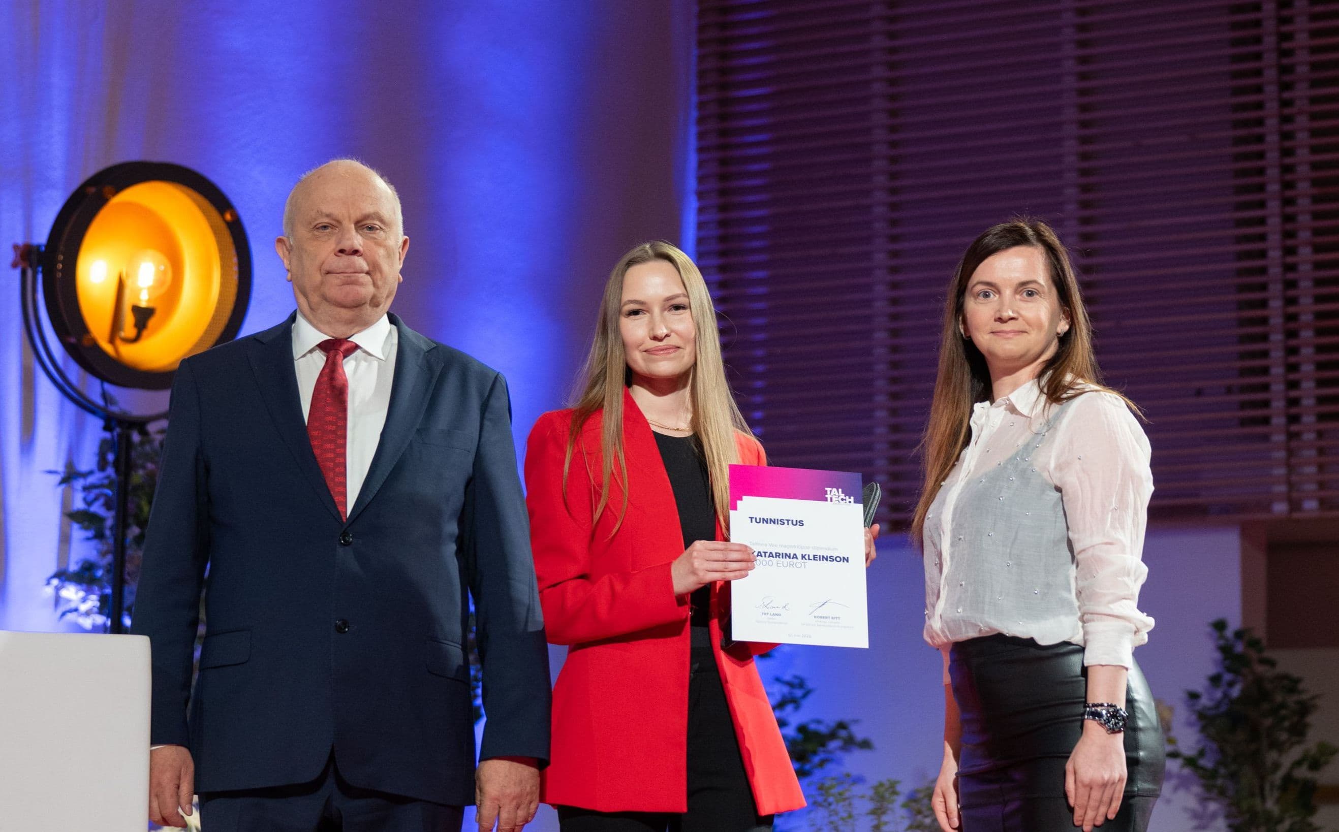 Three professionals, two women and one man, standing on a stage during an award ceremony.