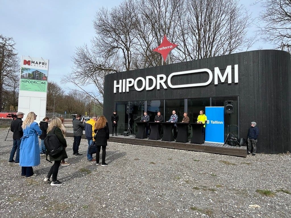 Modern black building with prominent "HIPODROMI" sign and people gathered outside for an event.