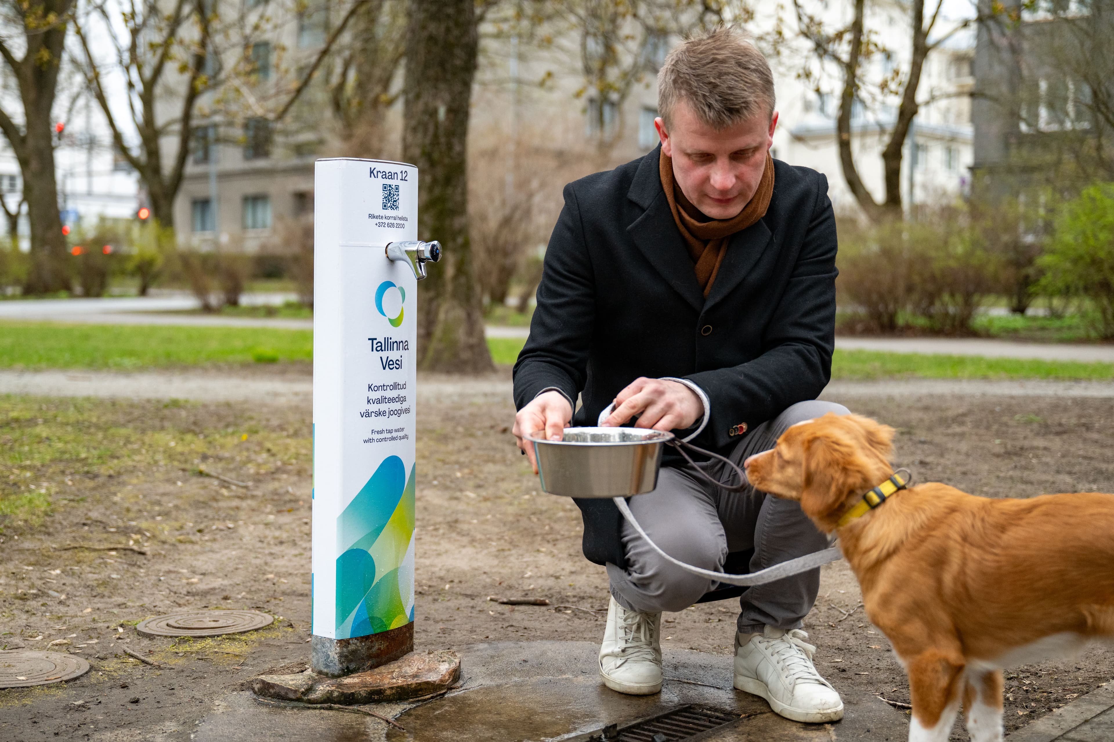A man pours water for his dog from a public outdoor drinking station.