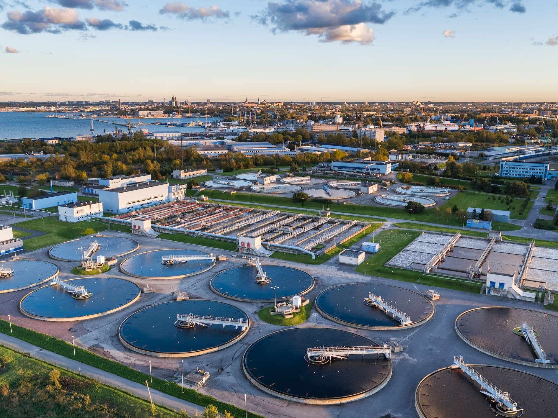 Aerial view of a wastewater treatment plant with large circular tanks and industrial buildings.